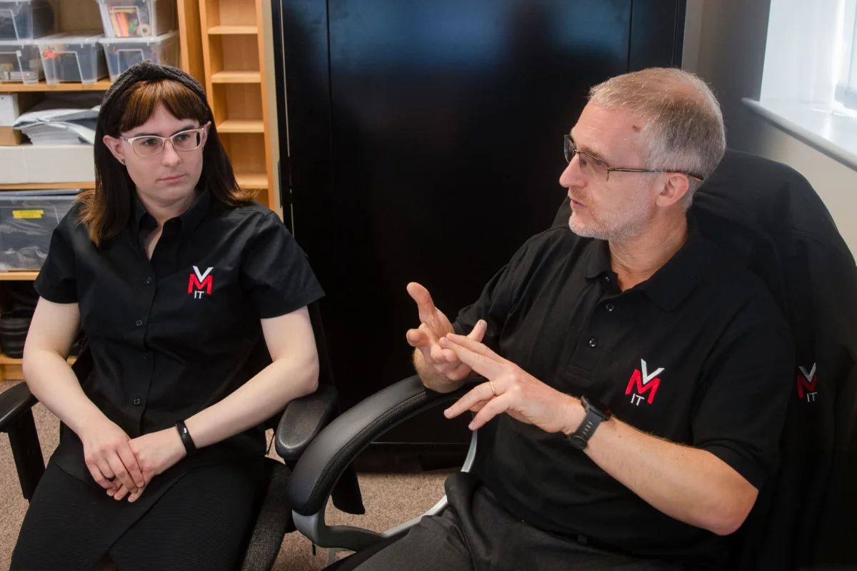 Nils and Martha seated in office chairs, speaking and gesturing during a discussion