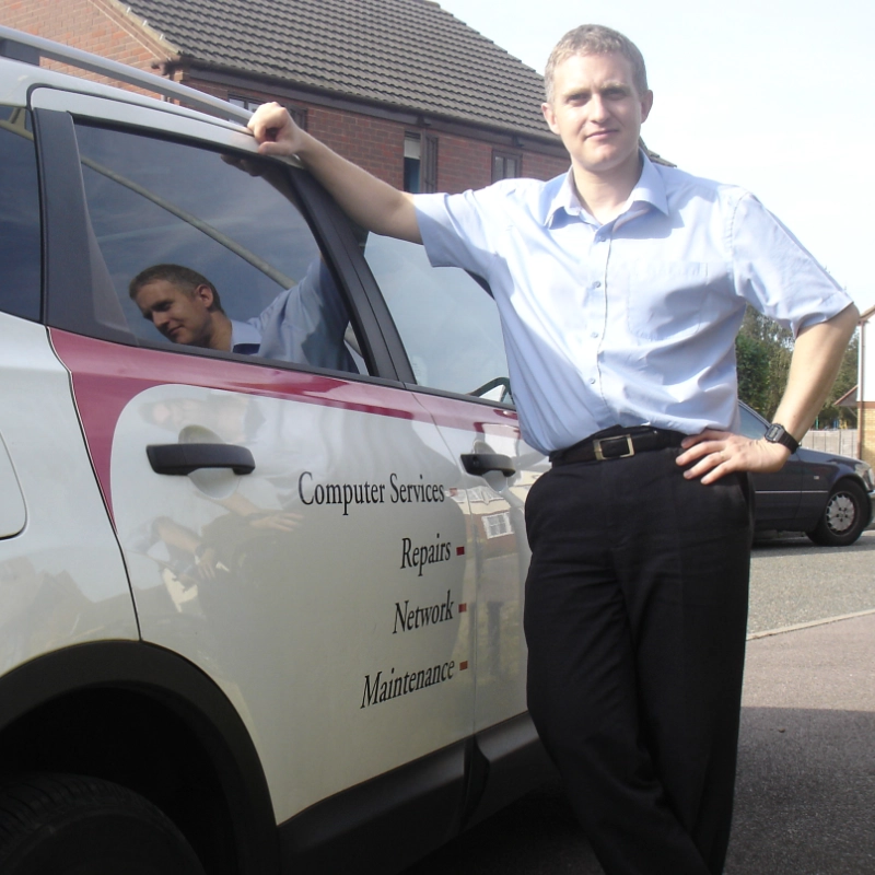 A man leaning on a parked car outdoors.